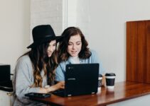 two woman sitting near table using Samsung laptop