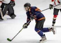 man in blue and white ice hockey jersey holding black and green hockey stick