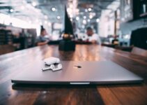 selective focus photography of white AirPods with charging case on silver MacBook on table