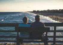 man and woman sitting on bench in front of beach