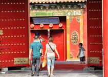 three people walking toward red building