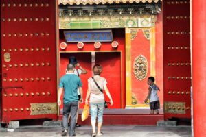 three people walking toward red building