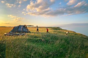 toddler walking on green grass with set-up tent during golden hour