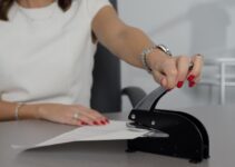 woman in white shirt holding pen writing on white paper