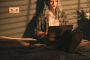 A Woman Lying on the Bed while Working on a Laptop