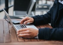 Crop businessman with laptop in street cafeteria