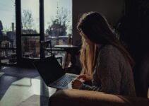 woman in gray sweater using laptop computer