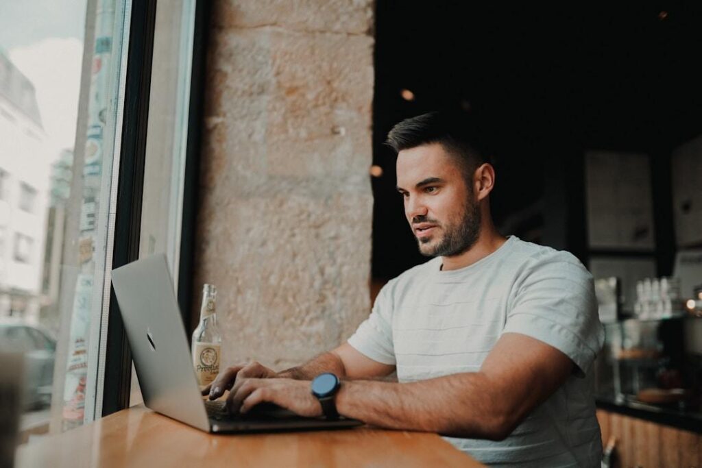 A man in a coffee shop researching inventory management on his computer