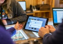 two people sitting at a table looking at a tablet