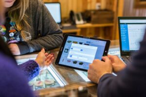 two people sitting at a table looking at a tablet