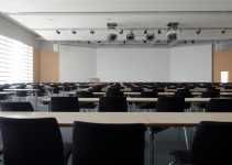 Spacious contemporary conference room with rows of tables and chairs, ready for meetings.