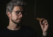 man in black crew neck shirt holding brown cigarette stick