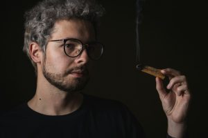 man in black crew neck shirt holding brown cigarette stick