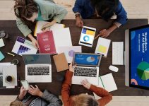 A diverse team collaborating on digital marketing strategies at a desk, using laptops and tablets.