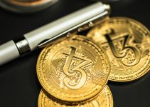 a pen sitting on top of a pile of gold coins