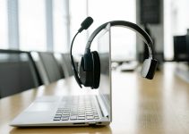 Sleek laptop with a wireless headset in a bright, modern office setting.