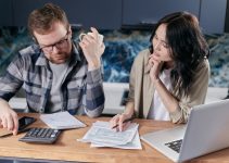 Free A couple reviews bills and documents on a laptop while discussing household finances. Stock Photo