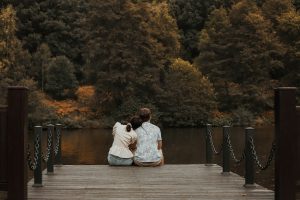 man in white dress shirt sitting on brown wooden dock during daytime