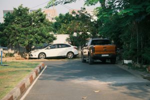 Cars are parked on a driveway near some trees.