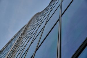 A tall glass building with a sky in the background