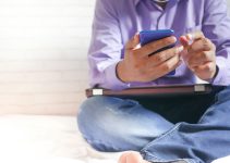 man in white dress shirt and blue denim jeans sitting on bed