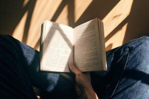 person holding book sitting on brown surface