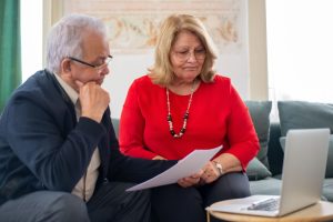 Elderly couple reviewing financial documents together at home in Portugal.