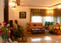 A living room with beige sofas, a wooden coffee table, and potted plants