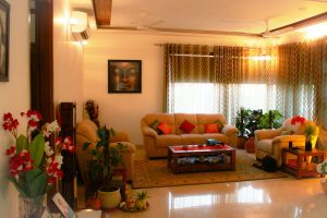 A living room with beige sofas, a wooden coffee table, and potted plants
