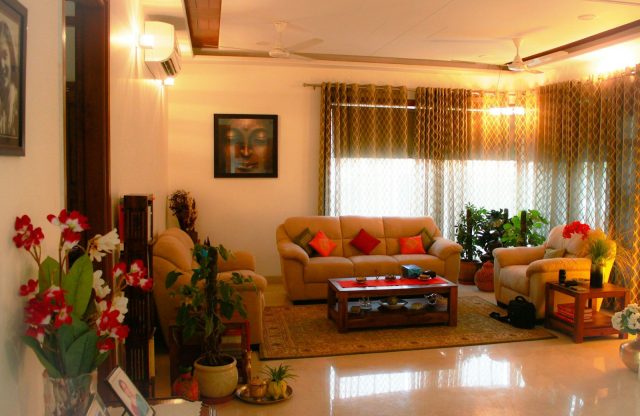 A living room with beige sofas, a wooden coffee table, and potted plants